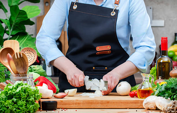 istock Housewife cuts onion into half in cozy kitchen with wooden table, kitchenware, vegetables, herbs and ingredients for cooking. Healthy vegan food, culinary, recipes, blogging 2208111170