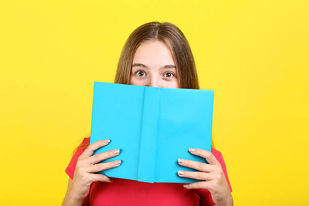istock Young girl with book on yellow background 2208118664