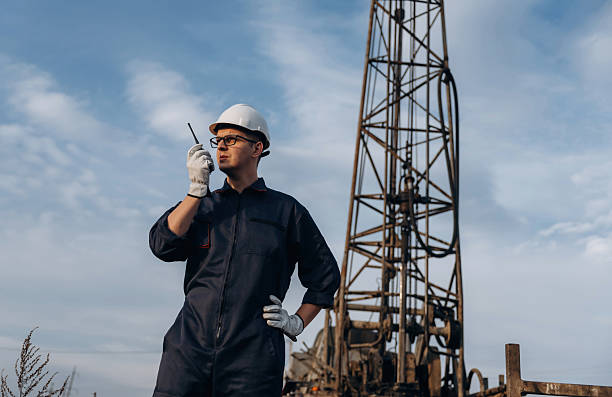 istock Talking by using walkie talkie. Construction worker is near boring drilling machine 2208119590