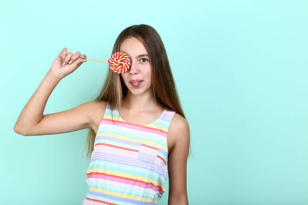 istock Young girl with lollipop on mint background 2208121038