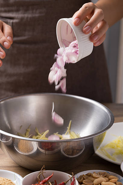 istock Spicy mango salad cooking, Hand adding sliced shallot in bowl and mixing with ingredients 2208121351