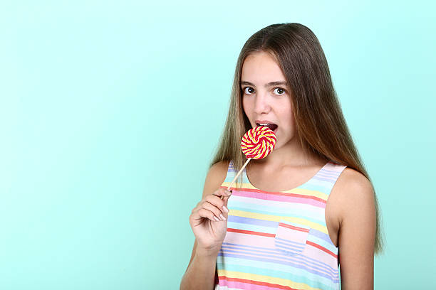 istock Young girl eating lollipop on mint background 2208123640