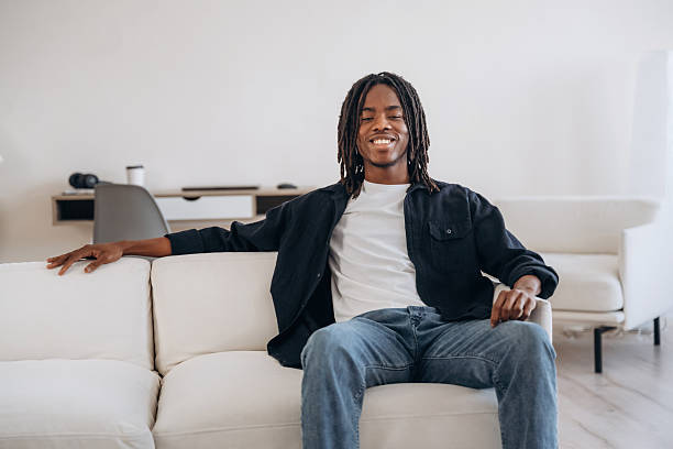 istock Looking forward. Cheerful African American guy is sitting on the sofa at home and smiling 2208124865