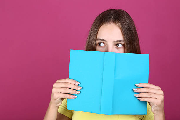istock Young girl with book on pink background 2208127554