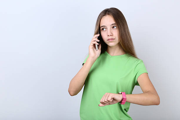 istock Young girl talking on a mobile phone on grey background 2208128175