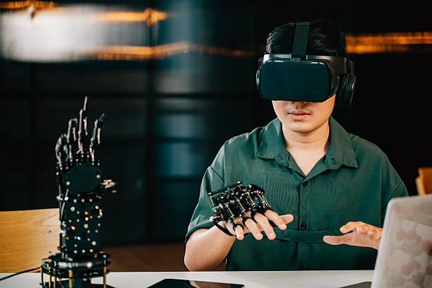 istock Asian teenager experiments with a robot arm project using VR glasses in a classroom. Embracing robotics programming merging technology and STEM education for futuristic learning. moves a robotic hand 2208128433