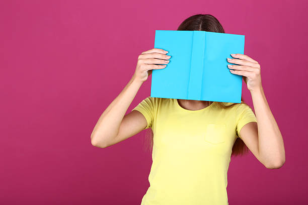 istock Young girl with book on pink background 2208129100