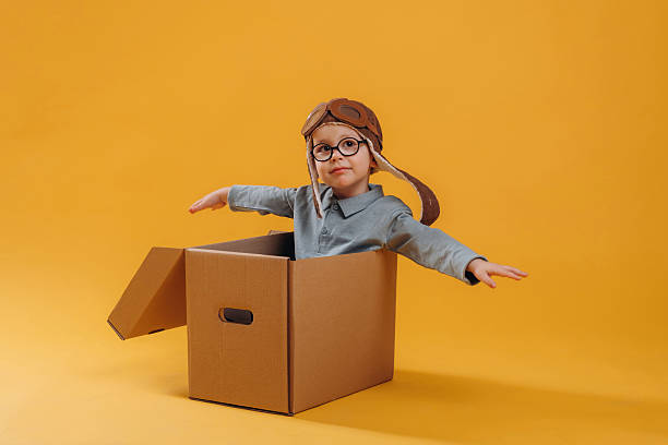 istock Aviator hat, in the box. Cute little boy is against yellow background 2208130532