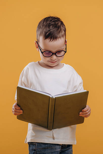 istock Reading the book. Cute little boy is against yellow background 2208130801