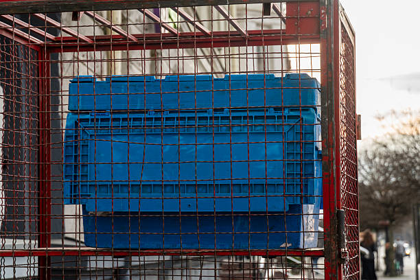 istock A red metal frame encases a bright blue storage container, illuminated by soft afternoon light in an urban area with blurred pedestrians nearby 2208132379
