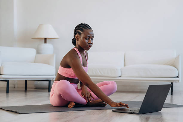 istock Taking online lessons by using laptop. Woman is doing yoga at home 2208132486
