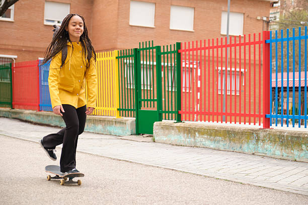 Young student skateboarding next to a colorful fence