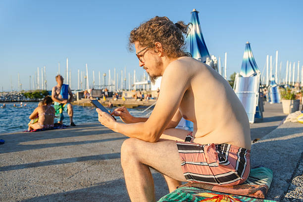 Man sitting on the beach and using his phone