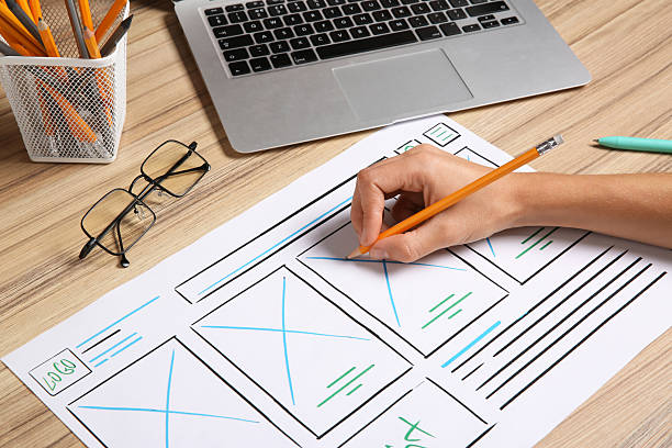 istock Developing UI design. Designer with smartphone creating website wireframe on paper at wooden table, closeup 2208136010