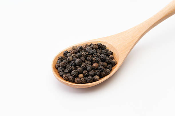 istock Whole black peppercorns on a wooden spoon 2208144308