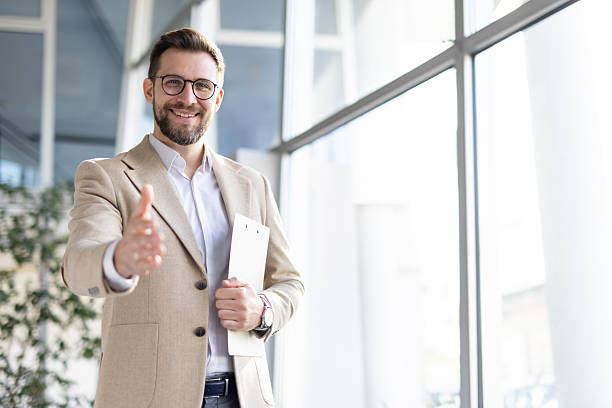 istock A smiling young businessman stretching hand for welcome 2208148762