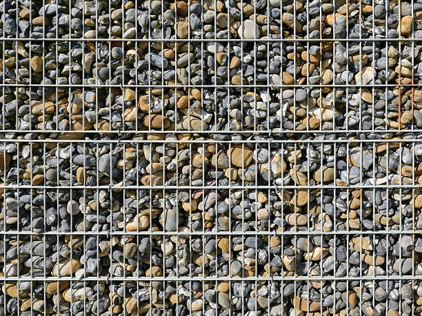 Gabion fence filled with flintstones, stable and durable. Controversial in design but functional as a visual and noise barrier in modern architecture.