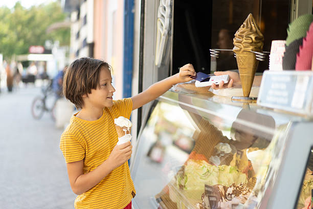istock Joyful Child Paying for Ice Cream at a Colorful Stand 2208152289