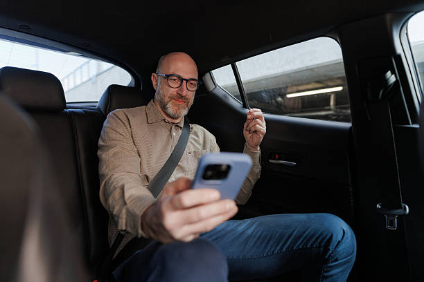 istock Man using smart phone while seated in the comfortable backseat of a car 2208153602