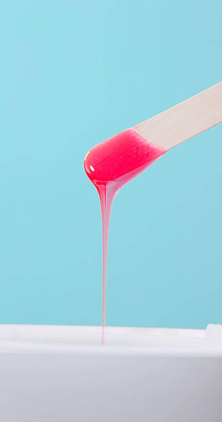 closeup view a wooden stick with pink hot wax on it in the medical beauty clinic - ready for hair removal procedures