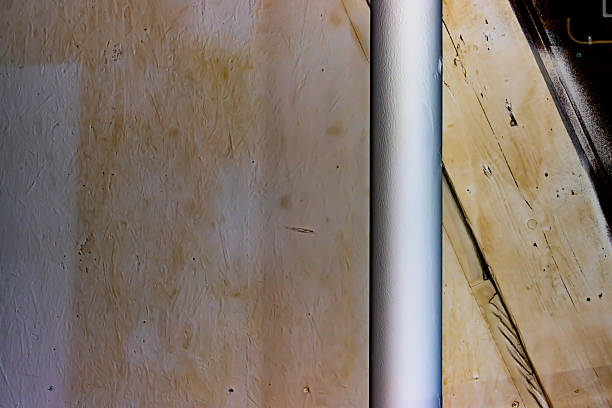 A textured wall featuring a metal pole and surrounding wooden elements under ambient lighting, highlighting simple surfaces and materials.