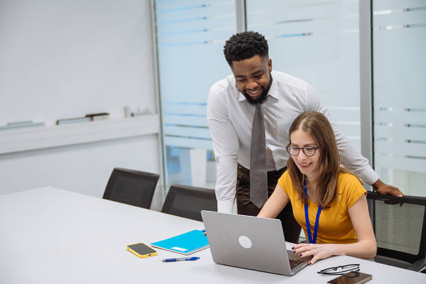istock Diverse colleagues engaged in a joyful discussion around a laptop in a modern office setting with glass walls 2208159995