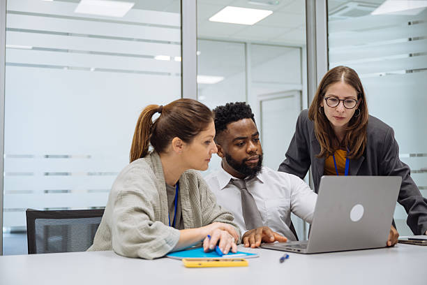 istock Diverse colleagues engaged in a joyful discussion around a laptop in a modern office setting with glass walls 2208160008