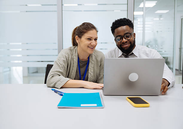 istock Diverse colleagues engaged in a joyful discussion around a laptop in a modern office setting with glass walls 2208160012