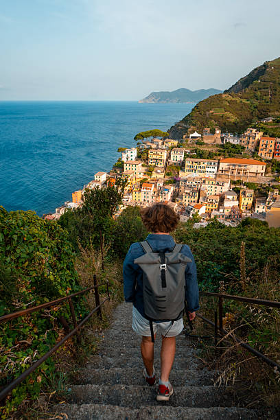 istock Hiker walks down steps above sea and village 2208161401