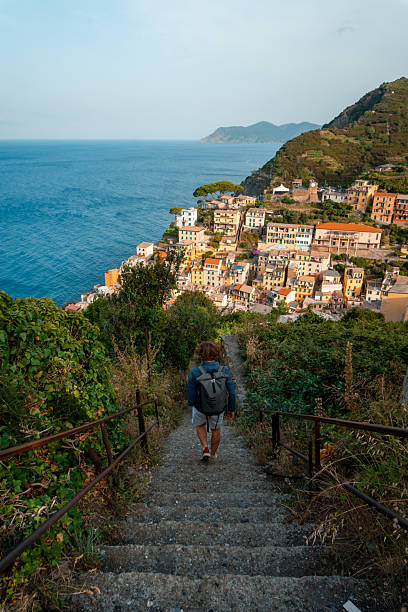 istock Hiker walks down steps above sea and village 2208161425