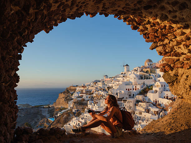 Woman with camer a looking with awe in Oia, Santorini  during experiential island hopping trip on Greek islands. Shot on medium format camera with immense quality