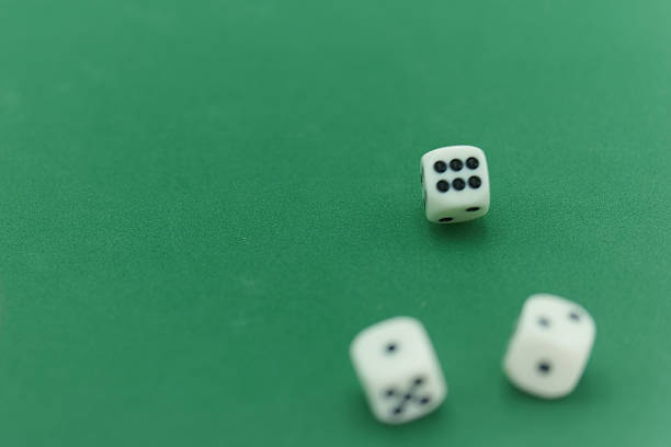 Three white dice are scattered on a vibrant green felt gaming table, showing various numbers. Friends gather around, enjoying a lively evening filled with games and laughter.