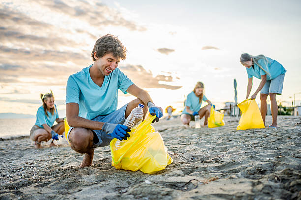 istock Male volunteer cleaning a polluted beach 2208165327