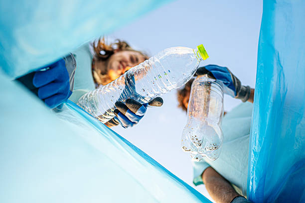 Volunteers putting plastic bottles in a trash bag