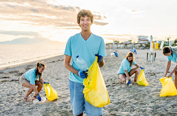 istock Young male volunteer cleaning a polluted beach 2208166433
