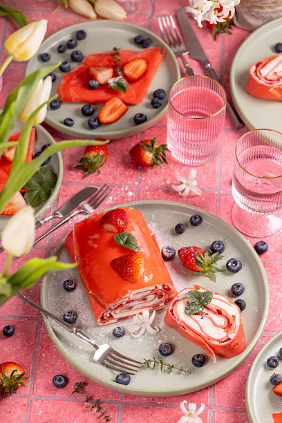 istock Pink strawberry dessert roll with blueberries and flowers on table setting 2208166435
