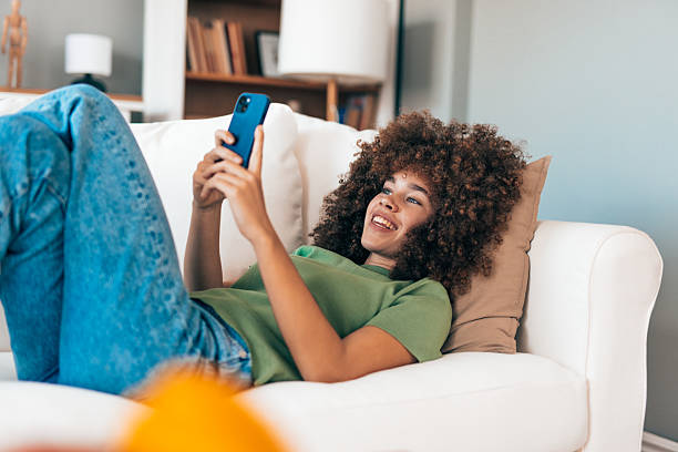istock Young woman relaxing on sofa using mobile phone at home 2208167355