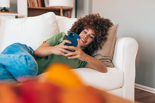 istock Young woman relaxing on sofa using mobile phone at home 2208167374
