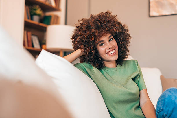 istock Young woman relaxing on sofa smiling at camera 2208167446