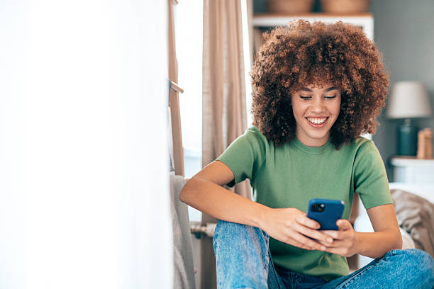 istock Young woman using mobile phone, relaxing at home 2208167496