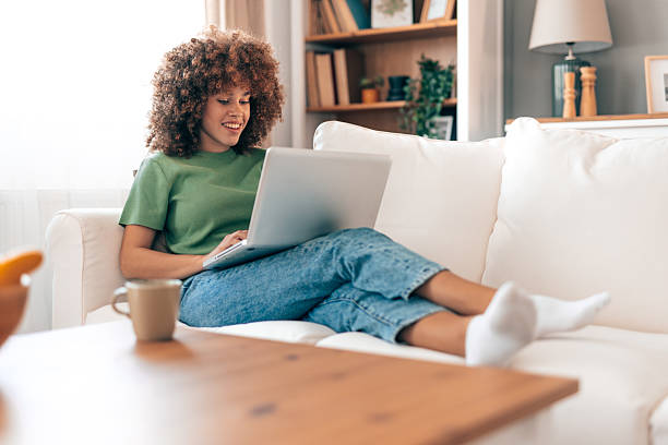 istock Young woman working from home, relaxing on the sofa with laptop 2208167502