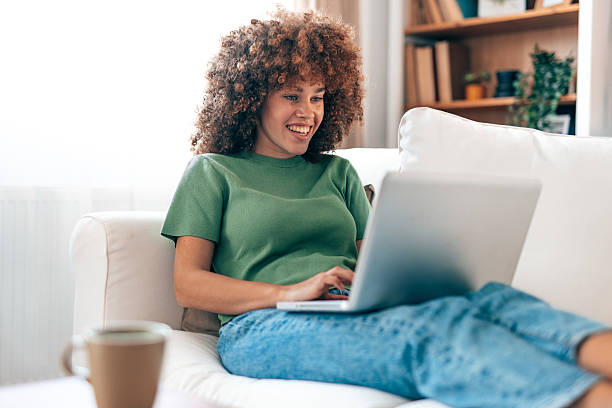 istock Young woman relaxing on sofa using laptop at home 2208167531