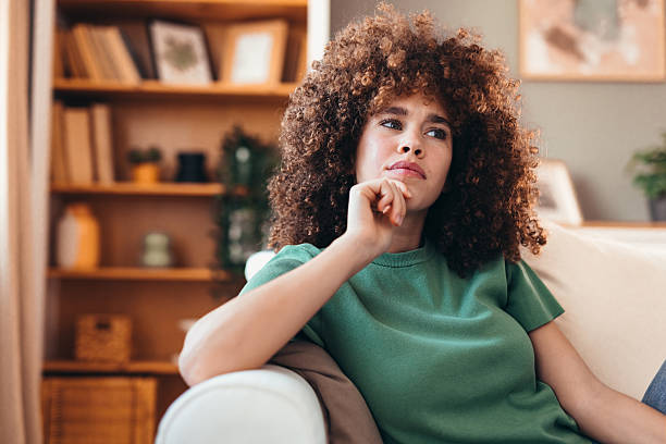 istock Young woman sitting on sofa and thinking about something 2208167550
