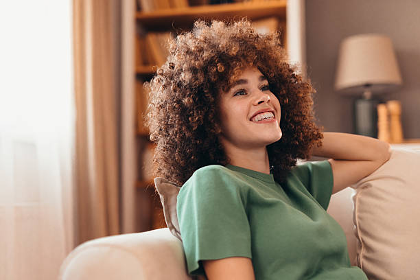 istock Young woman relaxing on sofa with hand behind head, smiling and looking away 2208167553