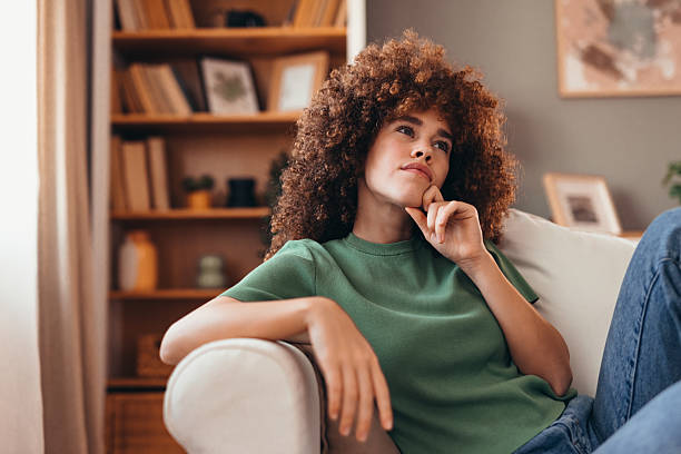 istock Young woman sitting on couch is thinking about something 2208167570