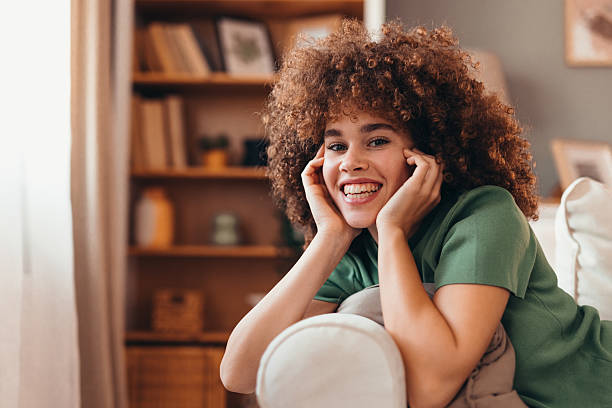 istock Young woman relaxing on sofa, smiling and looking at camera 2208167576