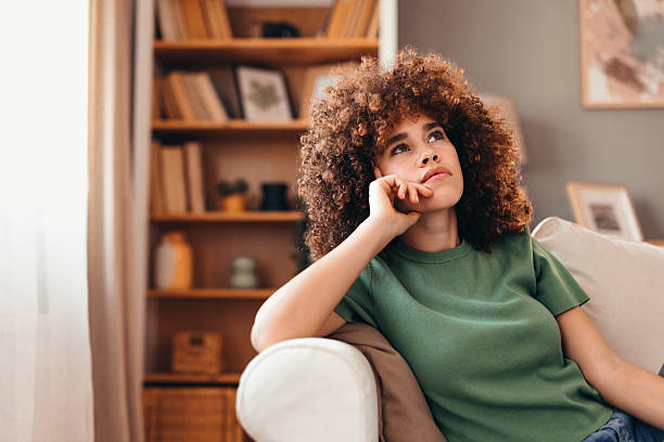 istock Young woman relaxing on sofa at home thinking about future 2208167582