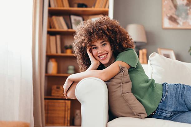 istock Young woman relaxing on sofa at home smiling at camera 2208167584