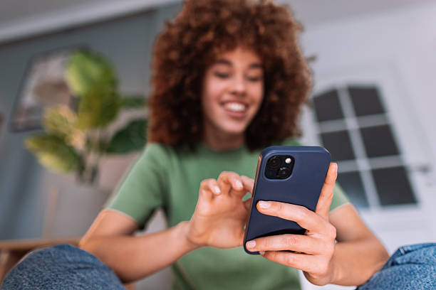 istock Young woman using mobile phone at home, browsing internet and smiling 2208167786