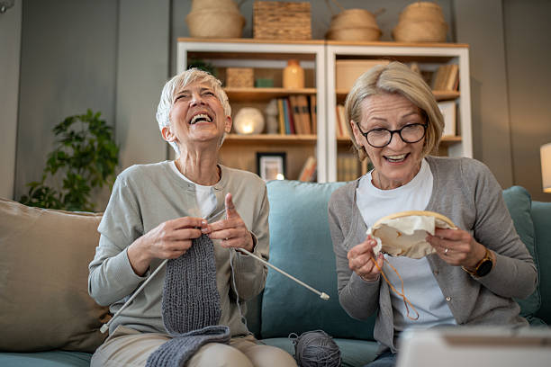 istock Two senior women laughing while knitting and embroidering at home 2208181271